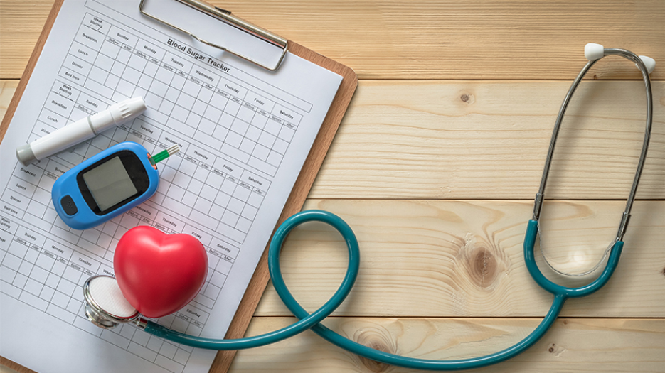 Picture of blood glucose monitor, stethoscope, and a heart model on top of a medical chart